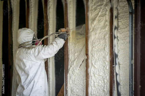 Worker spraying closed cell spray foam insulation on a home that was flooded by Hurricane Harvey