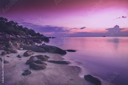 beautiful bright purple pink sunset by the sea, stones on the sand. Stunning scenery