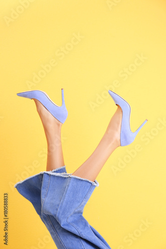 Young woman in stylish shoes on color background