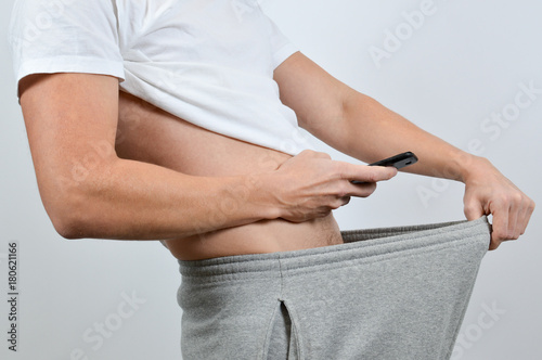 Man taking a picture of his penis with a smart-phone. A so-called dick pic