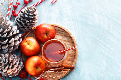 Seasonal and holidays concept. Winter hot tea in a glass with apples and spices on a wooden background. Selective focus, top view