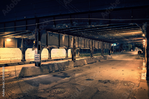 Dark Chicago city alley industrial train bridge underpass at night.