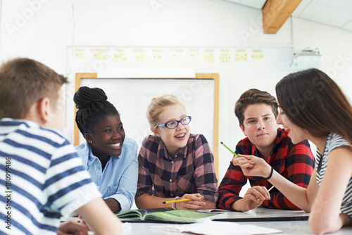 Group Of Teenage Students Collaborating On Project In Classroom