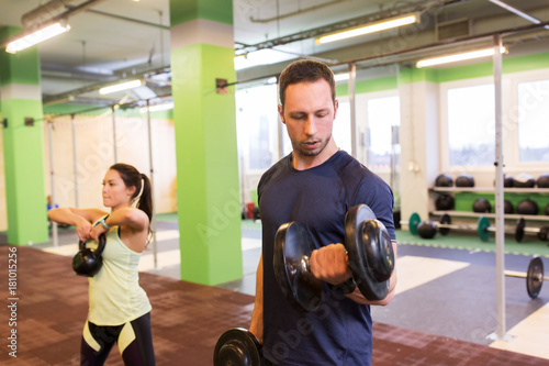 man and woman with kettlebell exercising in gym