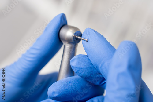 Dentist's hands with blue gloves configure dental drill in dental office. Close-up