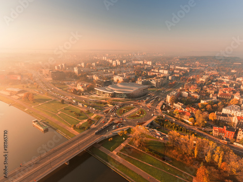 Aerial view of Krakow, Poland. Vistula river. Modern building Ice. Transportation, rush hour traffic, cars on highway interchange in city center. Morning time, orange and gold light. 