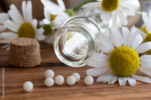 A bottle of homeopathic globules with chamomile flowers