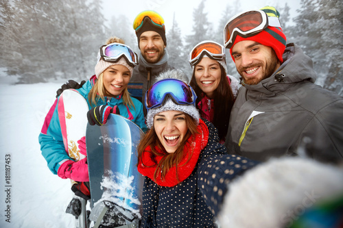 winter, extreme sport and people concept - friends having fun on the snow and making selfie