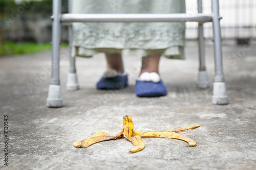 Careless elderly woman step over a banana peel on walkway