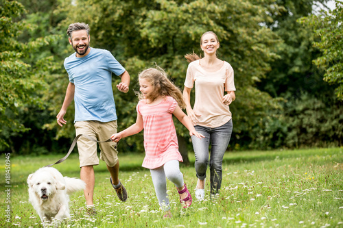 Familie mit Tochter und Hund spielen im Garten