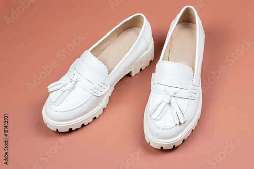 White female loafer shoes closeup on a warm brown background