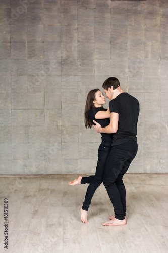 Guy and girl in dance movement. Young dancing couple hugging and looking at each other. Modern style couple performing romantic and sensual dance.