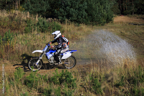 Enduro, motocyklista na motorze crossowym w kałuży.