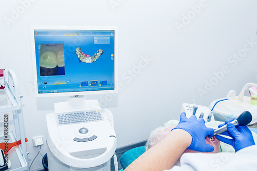Doctor modeling prosthesis using CAD CAM dental computer-aided machine in a highly modern dental laboratory. Dentistry, prostodontics, prosthetics and medical computer technology concept.