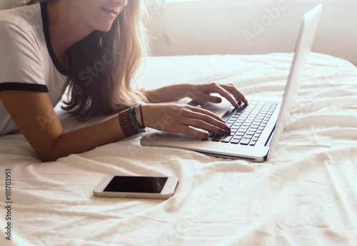 Attractive girl using computer on the bed.