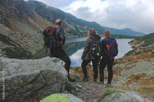 Troje młodych turystów na szlaku górskim podziwiający widoki