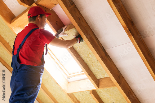 house attic insulation - construction worker installing rock wool in mansard wall