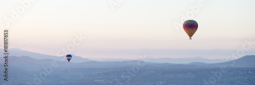 Hot air balloons over mountain landscape in Cappadocia, Goreme National Park, Turkey.