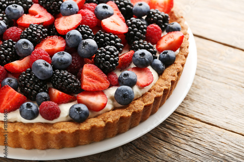 Sweet tart with berries in plate on grey wooden table