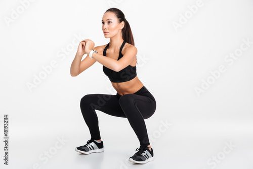 Portrait of a confident asian fitness woman doing squats