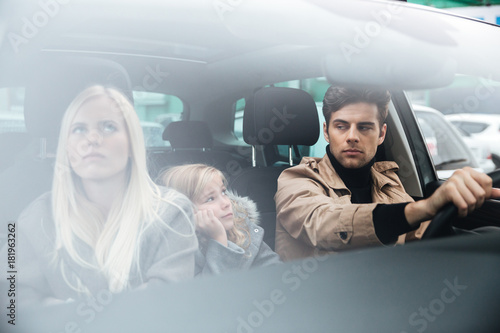 Angry displeased young family sitting in car after quarrel