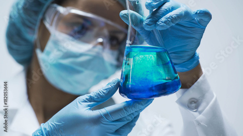 Researcher watching chemical reaction after adding test material into flask