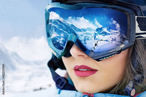 Portret młoda kobieta przy ośrodkiem narciarskim na tle góry i niebieskie niebo Pasmo górskie odbijający w masce narciarskiej