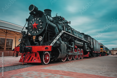 An old black Soviet steam locomotive with a red star on the hull