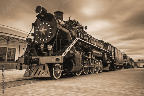 An old black Soviet steam locomotive with a star on the hull. Sepia