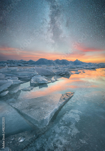 Frozen sea and night sky with stars. Beautiful natural seascape in the winter time