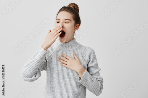 Tired woman yawning covering open mouth with hand need rest. Young female worker being sleepy head can't wake up having insomnia. Chain reaction