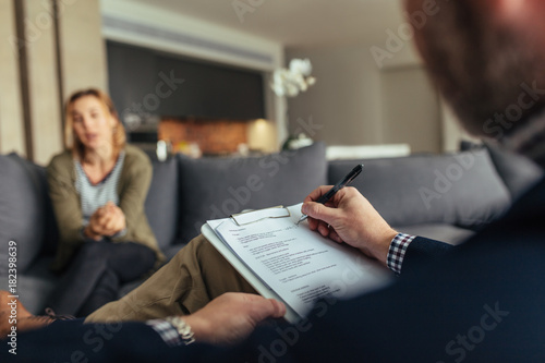 Psychologist writing notes during a therapy session with patient