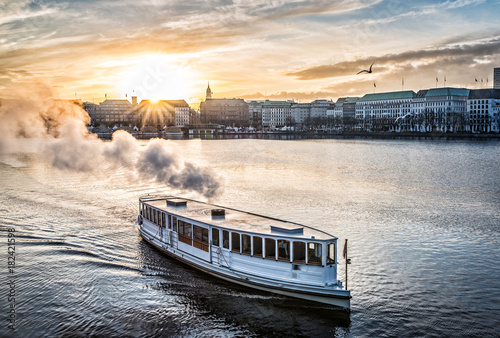 steamboat on Alster Lake in Hamburg, Germany with cityscape in background during sunset