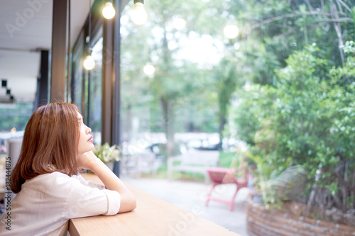 Beautiful asian girl looking through a window at cafe