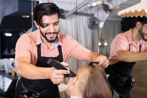 Cheerful male professional shaving female's hair
