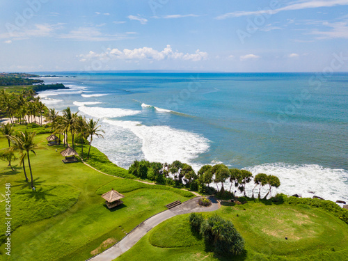 Aerial view to golf club with green hills, ocean and many palm trees near Tanah lot temple, Bali island, Indonesia.