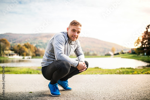 Handsome young runner squatting down.