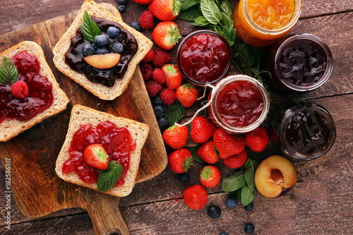 Sandwiches with plum, strawberry jam and fresh fruits on wooden background