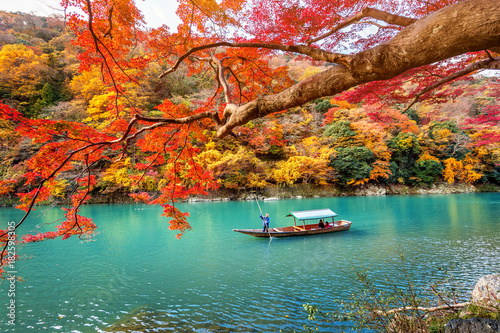 Boatman punting the boat at river. Arashiyama in autumn season along the river in Kyoto, Japan.