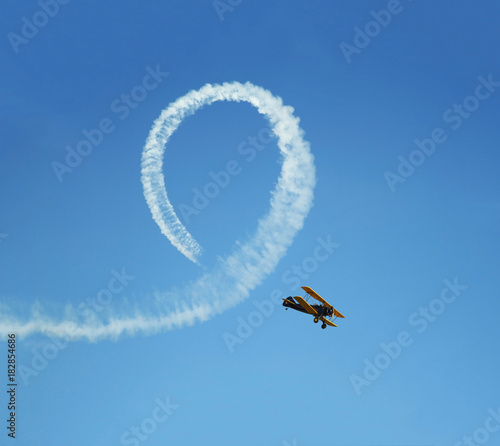 Vintage biplane does loop stunt with smoke trails