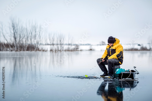 Mężczyzna lodowy połów na zamarzniętym jeziorze.