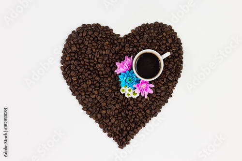 Coffee cup, flowers and coffee beans in a form of a heart isolated on white background.