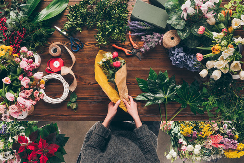 cropped image of florist wrapping bouquet in yellow pack paper