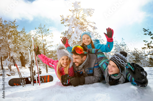 smiling family enjoying winter vacations in mountains on snow