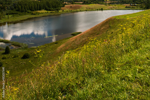 Landscape with a hill, a river and a reflection of clouds