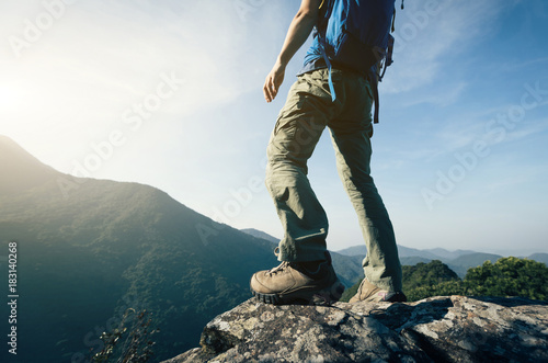 successful female backpacker enjoy the view cliff's edge