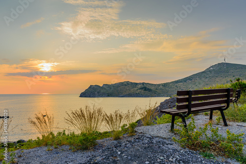 Beautiful sunset on the sea. Viewpoint with a bench on top of a hill. Skala village on Patmos island, Dodecanese, Greece.