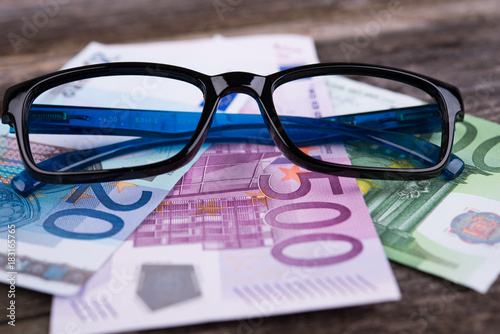 glasses frame with money on wooden ground
