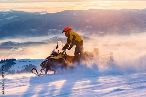 A man is ridind snowmobile in mountains.