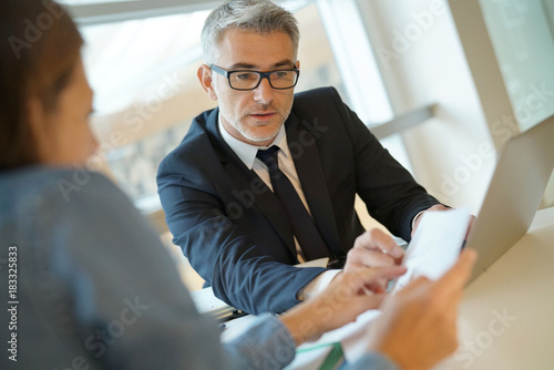 Woman in banker's office signing financial loan for project